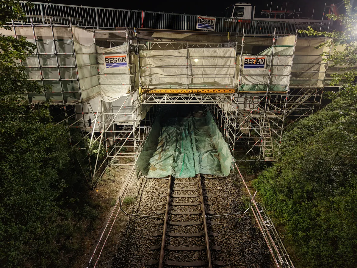 Beleuchtetes Brückengerüst bei Nacht über Bahngleisen